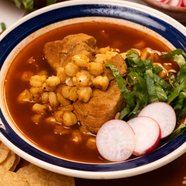 A bowl of traditional pozole recipe with pork and hominy, garnished with fresh toppings.